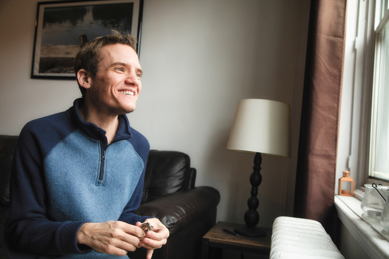 Autistic at home smiling as he looks out of the window